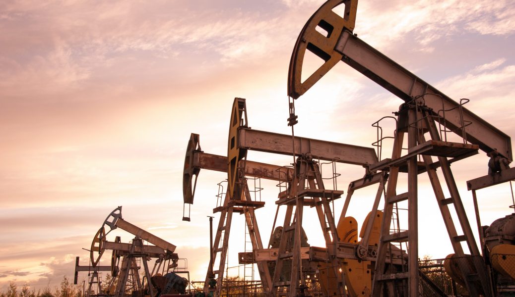 Oil pump jacks at sunset sky background. Toned.