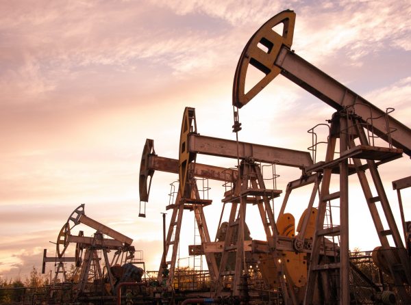 Oil pump jacks at sunset sky background. Toned.